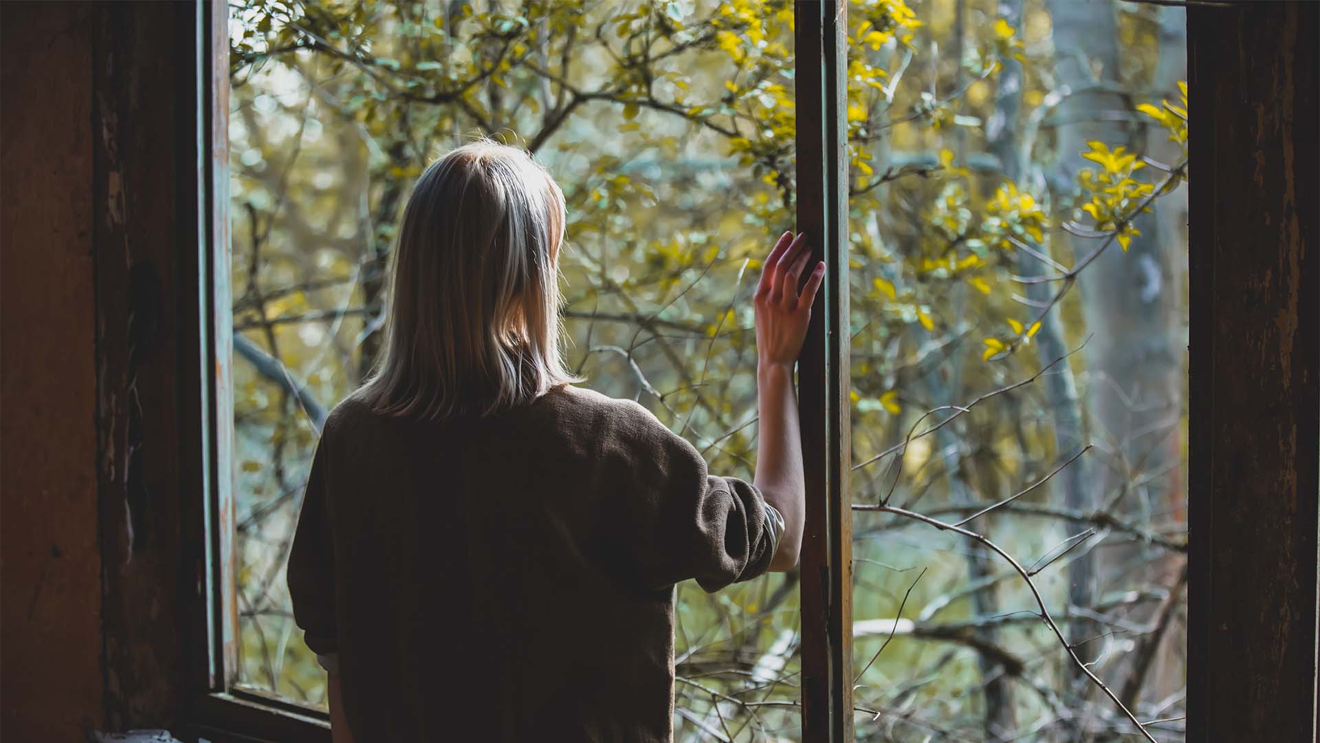 Ensam kvinna tittar ut geom ett fönster